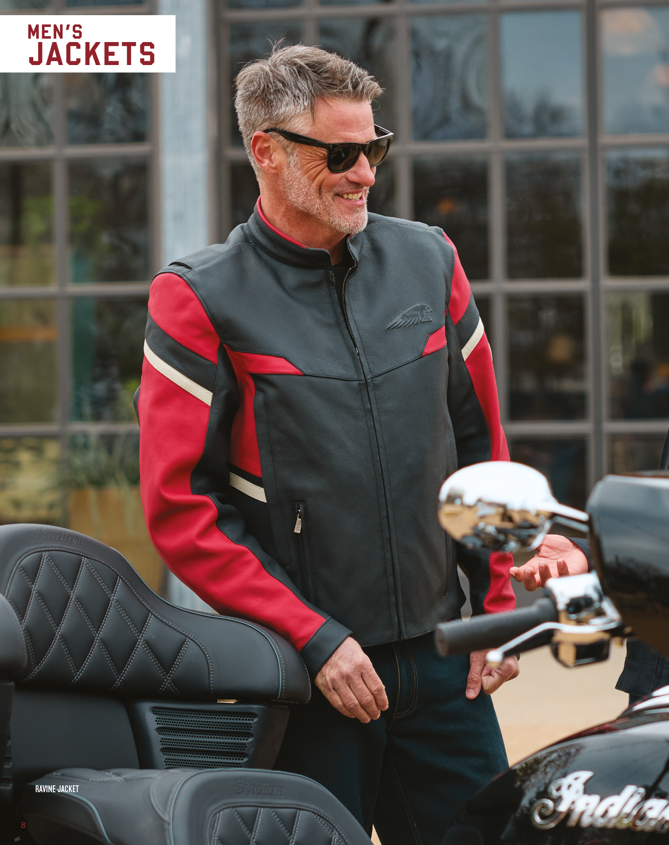 A man wearing a red and black jacket is standing next to a motorcycle. AI generated content